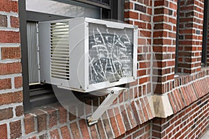 Window Air Conditioner in the Window of an Old Brick Apartment Building in Queens of New York City