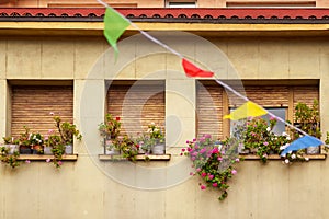 Window of an ancient residential building with flowers, festive flags