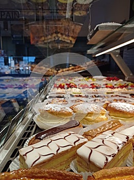 Window of a bakery in France with millefeuille, eclair and tropezienne specialities in foreground