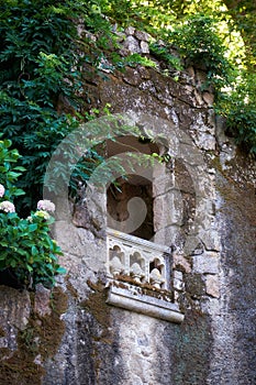 A window with a balcony in the old wall of Quinta da Regaleira p