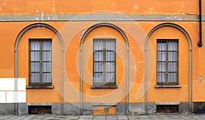 Window bars and closed windows on an orange wall