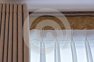 Window beige curtains and white tulle on the curtain rod