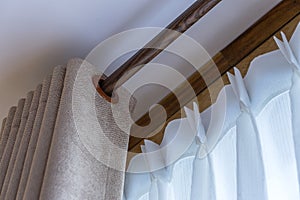 Window beige curtains and white tulle on the curtain rod