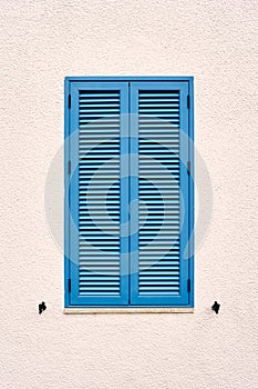 Window with blue blinds on the wall of the house. Close-up