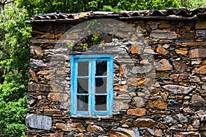 Window with blue rustic wood trim set in the stone wall of an old house