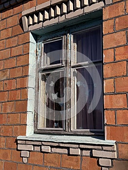 Window in a brick house. Dilapidated window frame.
