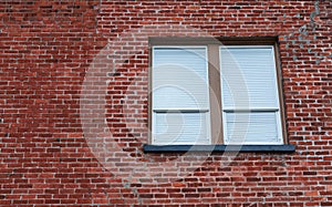 Window in Brick Wall. Window with closed blinds in a urban red bricks clinker house