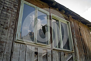 Window with broken glass in old building. Wooden window frame with partially broken glass in old abandoned wooden