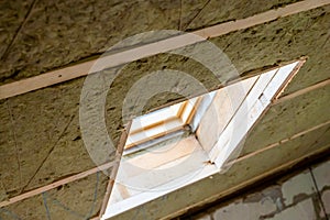 A window built into a roof insulated with green mineral wool close-up