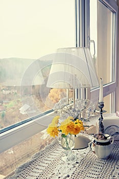 The window of the cafe overlooks the autumn romantic landscape. Interior with lamp and candle on the table with lace tablecloth.