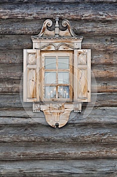 Window with carved architraves in a wooden hut.