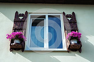 Window with carved doors and with flower pots on the facade of t