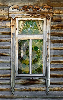 Window with carved platbands on an old wooden building. Front view.