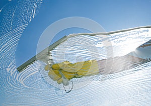 Window cleaner cleaning window with squeegee and wiper on a sunny day