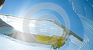 Window cleaner cleaning window with squeegee and wiper on a sunny day