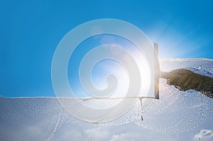 Window cleaner cleaning window with squeegee and wiper on a sunny day with a bright blue sky