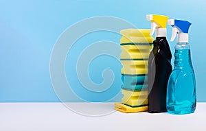 Window cleaner in a colorful plastic spray bottles and sponges on blue background. Cleaning concept