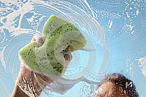 Window cleaner using a sponge and soap suds to wash a window