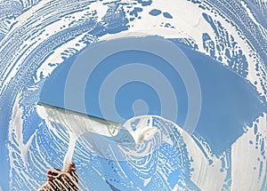 Window cleaner using a squeegee to wash a window photo