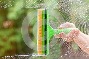 Window cleaner using a squeegee to wash a window. Clean horizontal bar