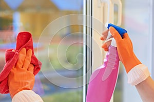 Window cleaning. Hands in gloves with a spray and a rag