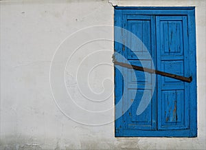 Window with closed blue shutters on the old building