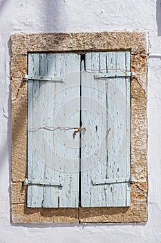 Window closed wood shutter on white wall. Cyclades house front view, Greek island architecture
