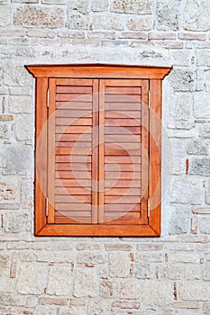 Window with closed wooden shutters on a stone wall