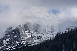 Window in the clouds shows the mountain top covered in snow and some blue sky