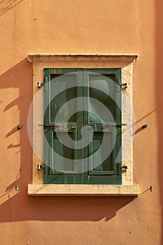 Window of a colorful house with green closed shutters in Malcesine in Italy