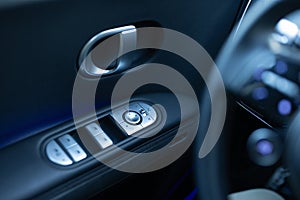 Window control buttons in modern luxury electric car. Car leather interior details of door handle with windows controls