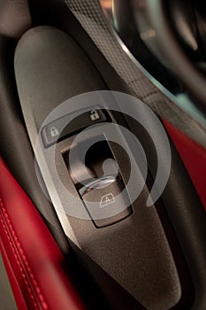 Window controlling button on the door console, black leather red lether, close-up. Ð¡ar interior details