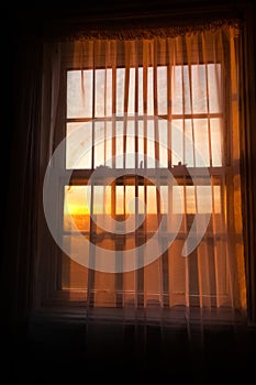 Window with a curtain drawn and the sun setting