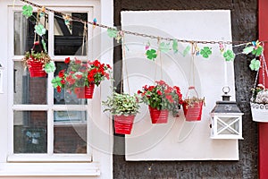 Window decorated with flower pots hanging at a chain