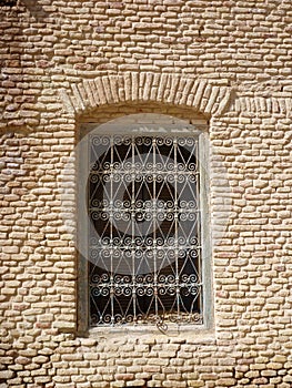 A window with a decorative bars in a brick wall