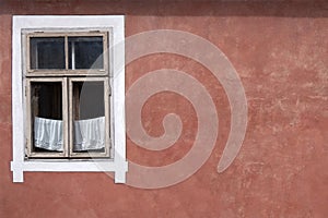 Window on an empty red wall of an old house