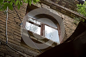 Window on the facade of an old abandoned brick townhouse of the 19th century, view from the bottom up