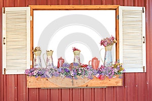Window frame decorated by flowerpot hanging below and some flowers in vintage vase with white background inside.