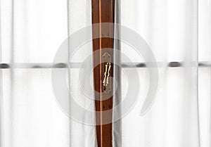 Window frame detail with vintage handle and white curtains