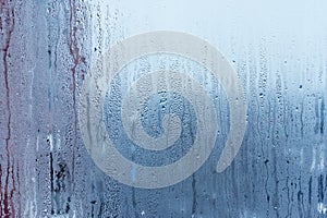 Window glass with condensation, strong, high humidity in the room, large water droplets flow down the , cold tone