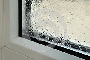 Window glass with drops of condensate indoors, closeup