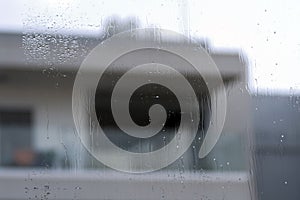 Window glass with raindrops and house shape