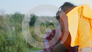 In window glass is reflected , smiling woman in headphones, in gloves, Cleaning Window by spraying Cleaning Products