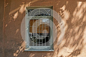 Window with gray iron grill on brown concrete wall