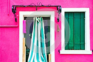 Window with green shutters and door on the pink wall