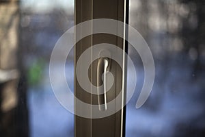Window handle. Plastic windows in the apartment. Handle for opening the window for ventilation. The closed window is white.