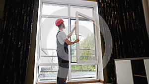 Window installer adjusting plastic windows with level tool in room