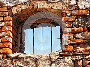 Window with iron bars in a rough wall made of natural stone