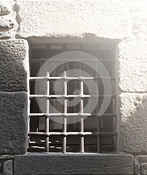 Window with iron grating on stone wall on sunlight