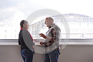 Window, mature couple and talking for communication, conversation and discussion of retirement holiday. Smile, elderly
